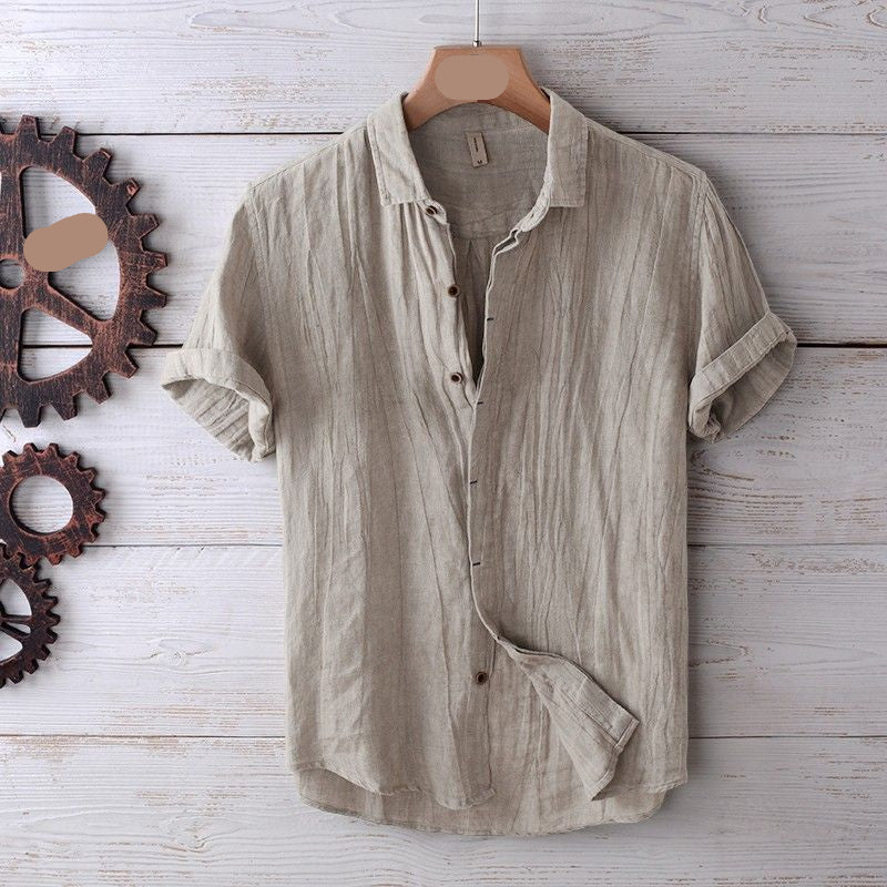 Beige short-sleeve shirt on a hanger against a wooden background with metal gears.